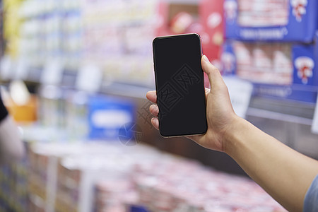 手机卖场超市里拿着手机的手背景