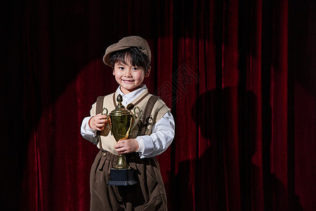 舞台上手拿奖杯的小男孩图片