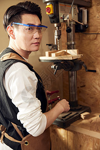 男性工匠使用钻木机打孔图片