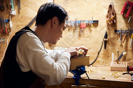 男性工匠夜间工作台上打磨木块背景