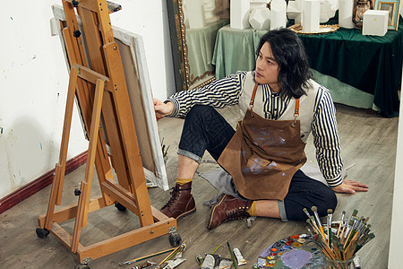 工作室画室坐在地上画油画的文艺男青年背景