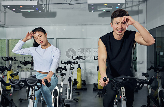 健身房动感单车激烈训练的运动情侣图片
