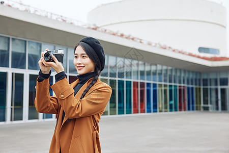 博物馆外的青年女性手拿相机形象图片