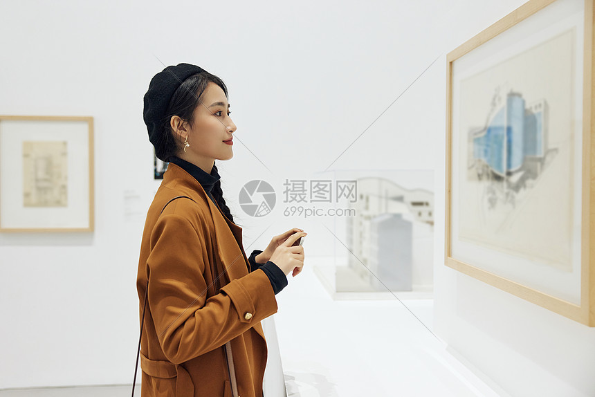 文艺女青年看展拿手机拍照图片