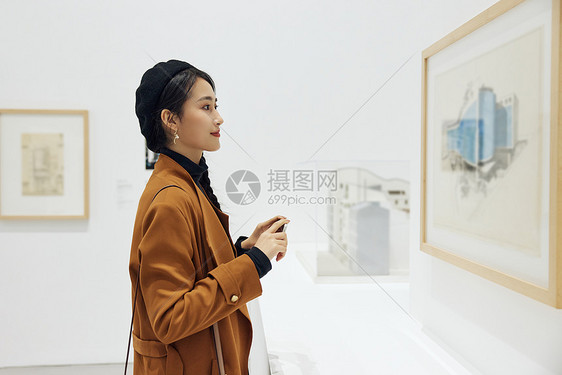 文艺女青年看展拿手机拍照图片