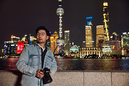 手拿相机的风光摄影师拍摄城市夜景图片