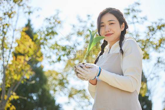 双手捧着花苗的环保女性图片