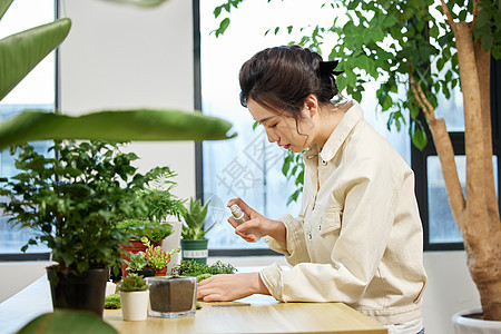 使用喷壶对植物喷水的女性图片