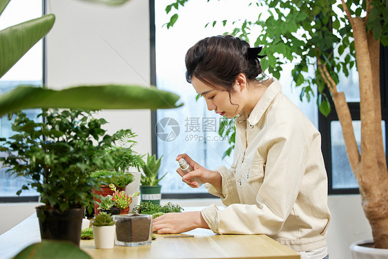 使用喷壶对植物喷水的女性图片