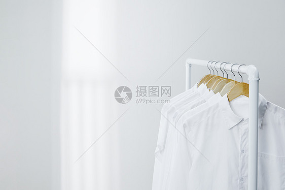 白色衣架上晾晒着的衬衫图片