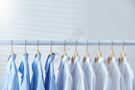 白色衣架上晾晒着的蓝白衬衫图片