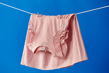 晾衣绳上晾晒着的粉色裙子图片