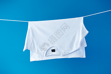 白蓝色背景晾衣绳上晾晒着的白T体恤衫背景