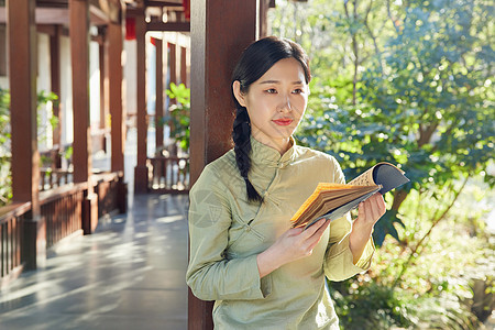 公园赏植看书的气质美女背景图片