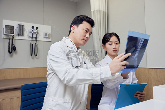 两名医生手拿X光讨论患者病情图片