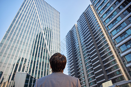 仰望摩天大楼仰望城市的商务男青年背影背景