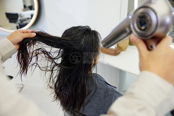 理发师给女性顾客吹头发特写图片