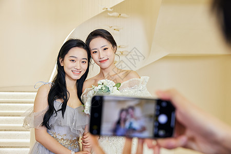 伴娘与新娘用手机拍照纪念背景图片