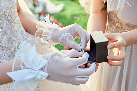 户外婚礼上的新娘为新郎佩戴戒指特写图片