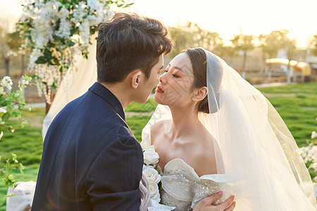 户外举行婚礼的新郎新娘甜蜜接吻图片