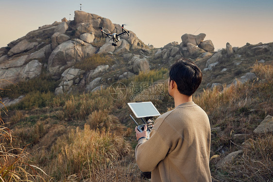 航拍摄影师登山使用无人机拍摄背影图片