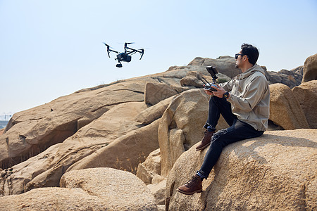 登山运动航拍摄影师山顶使用无人机拍摄风光背景