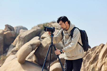 风光摄影师户外登山用三脚架拍摄图片