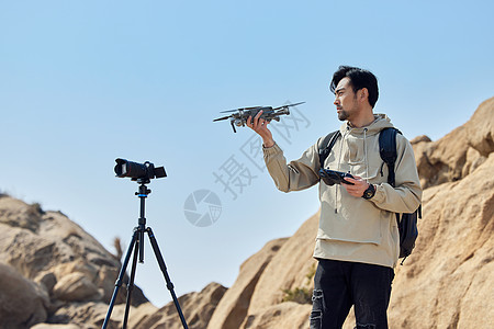 登山户外航拍摄影师山顶使用无人机拍摄风景风光背景