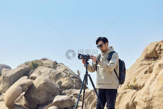 户外登山的风光摄影师使用三脚架拍摄山景图片