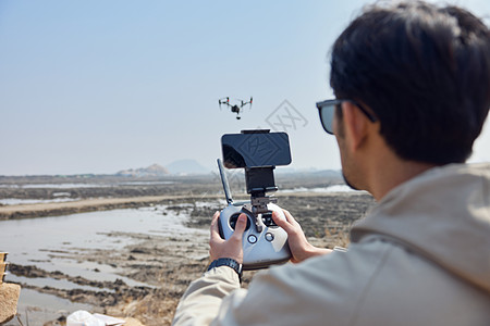 航拍摄影师户外操控无人机背影图片