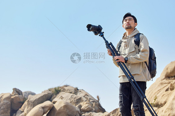 风光摄影师扛三脚架登山堪景图片