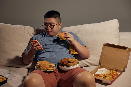 肥胖男士沙发玩手机吃夜宵图片