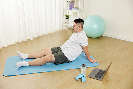 肥胖男青年瑜伽垫上擦汗休息图片