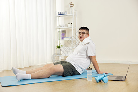 肥胖男青年瑜伽垫上休息图片