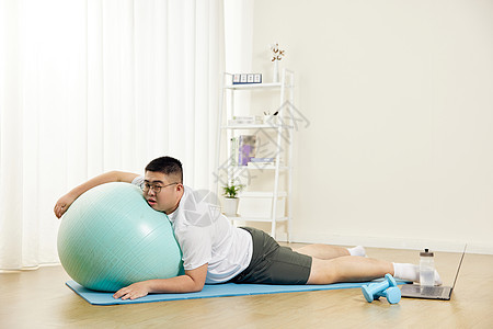 胖男生瑜伽球上休息图片