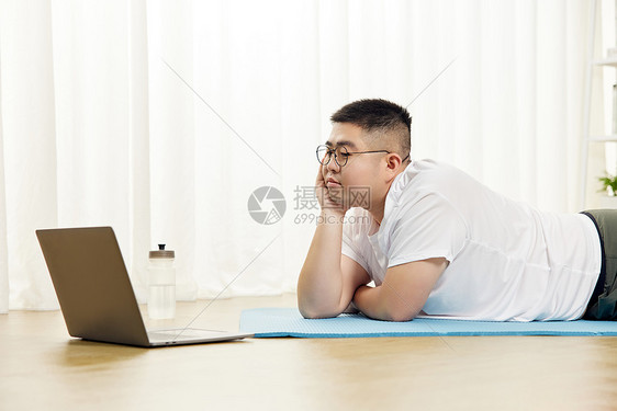 胖子男生瑜伽垫上看电脑图片