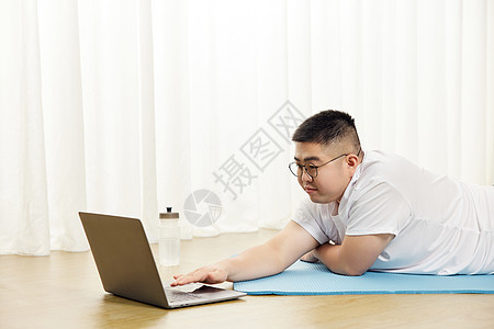 胖子男生瑜伽垫上看视频教程图片