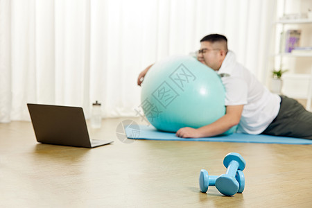 胖子男士趴在瑜伽球上休息图片