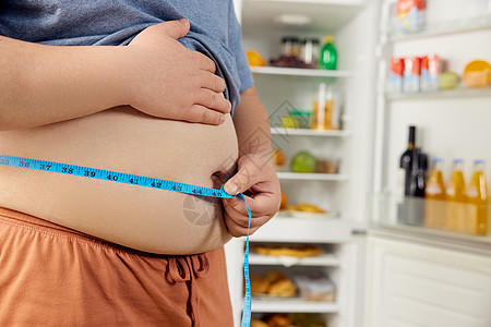 测量腰围肥胖男性居家量腰围特写背景