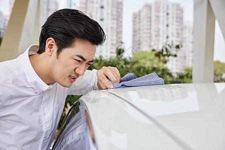 年轻男士用毛巾清理车顶图片