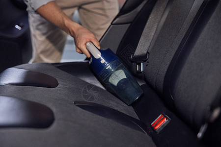 新能源汽车制造男士使用车载吸尘器清理汽车特写背景