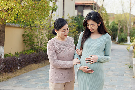 妈妈陪怀孕的女儿外出散步背景图片