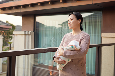 阳台上中年妇女抱着新生婴儿宝宝高清图片
