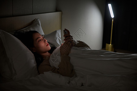熬夜玩手机的青年女性背景图片