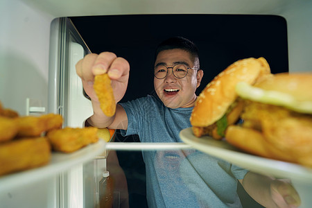 肥胖男青年冰箱挑选美食图片