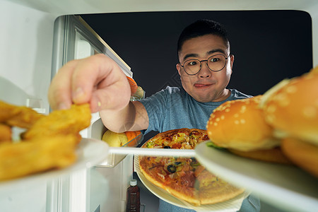 肥胖男青年在冰箱挑选美食背景图片