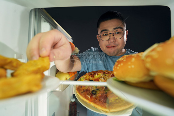 肥胖男青年在冰箱挑选美食图片