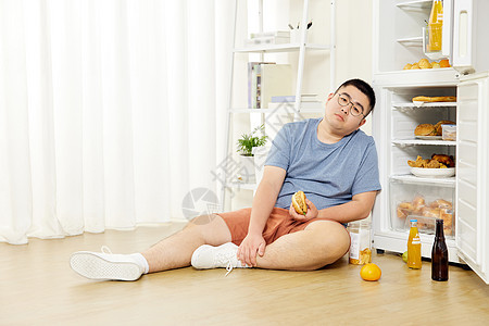 肥胖男士坐在冰箱旁图片