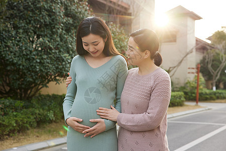 母亲陪怀孕的女儿外出散步背景图片