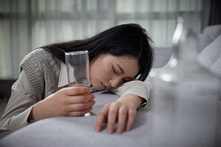 伤心的女人悲伤难过喝酒的青年女性醉倒在家背景